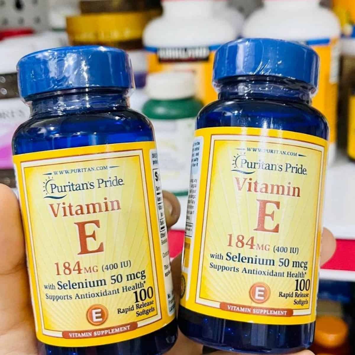 Puritans Pride Vitamin E 184Mg 400Iu 100V Lọ Puritans Pride Vitamin E 184mg 400IU đặt trên nền sáng với nhãn màu xanh vàng