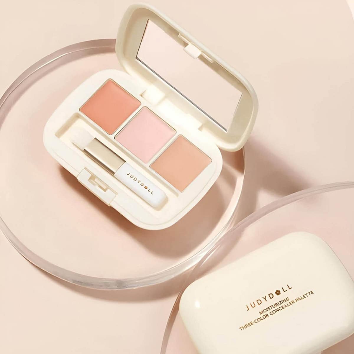Judydoll Three-Color Concealer Palette Tông Hồng Đào Bảng Judydoll ba ô màu hồng đào và beige đặt cạnh vỏ hộp màu kem